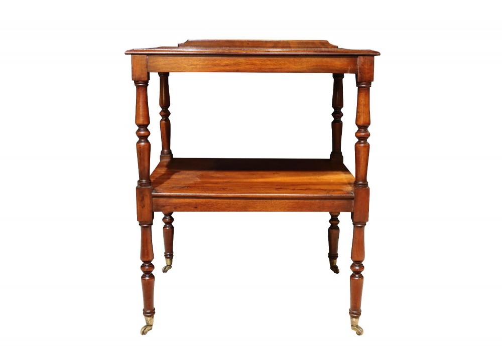 An early 19th-century mahogany two-tier side table featuring turned legs with brass castors and a lower shelf.