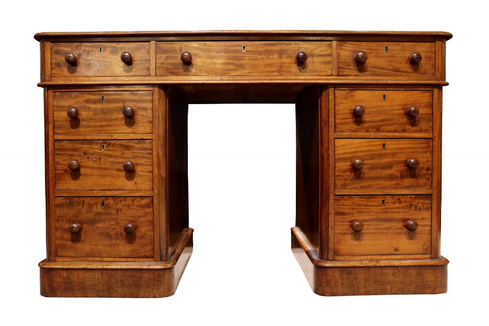 A Victorian mahogany pedestal desk with nine drawers featuring turned wooden handles and a solid plinth base.