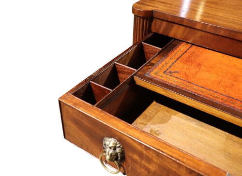 A Regency mahogany writing table with two drawers featuring brass lion-mask ring handles and reeded legs on brass castors. View IV