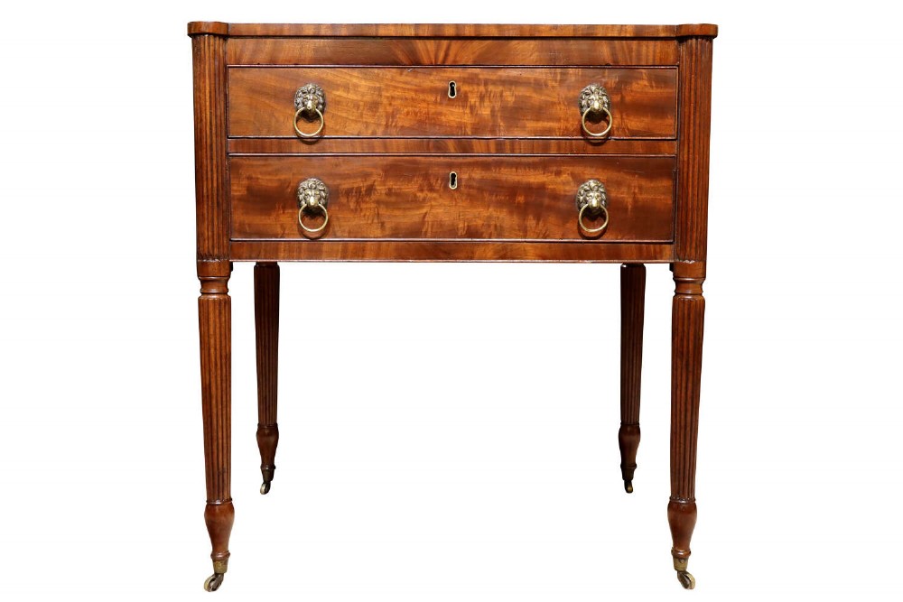 A Regency mahogany writing table with two drawers featuring brass lion-mask ring handles and reeded legs on brass castors. View VI