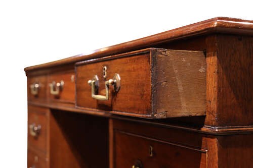 An Edwardian mahogany pedestal desk featuring nine drawers with brass drop handles and a central kneehole opening. View VI