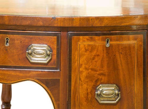 A small George III mahogany bow-front sideboard featuring purpleheart crossbanding, brass handles, an arched central kneehole, and tapered legs. View VI