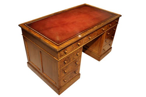 A Victorian burr walnut pedestal desk featuring nine drawers with turned wooden knobs and a red leather gilt-tooled writing surface. View V