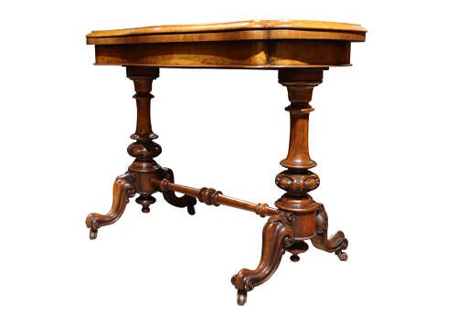 A Victorian burr walnut card table with a fold-over swivel top, carved twin pedestal supports, turned stretcher, and splayed legs on castors. View IV