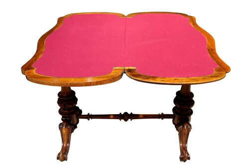 A Victorian burr walnut card table with a fold-over swivel top, carved twin pedestal supports, turned stretcher, and splayed legs on castors. View VI