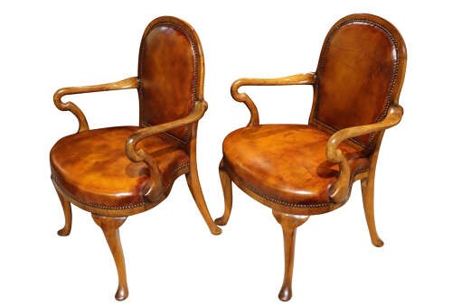 A pair of early twentieth-century walnut armchairs featuring warm tan leather upholstery with brass studding and cabriole legs. View II
