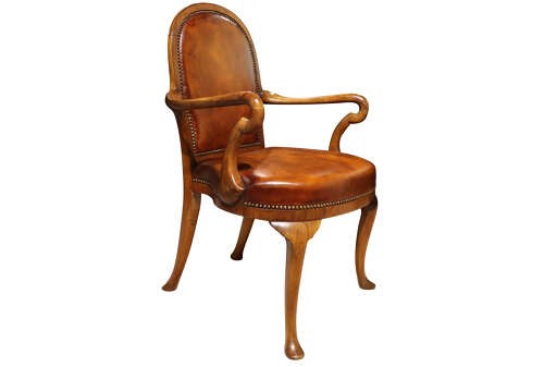 A pair of early twentieth-century walnut armchairs featuring warm tan leather upholstery with brass studding and cabriole legs. View V