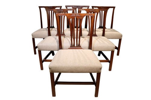 A set of six Georgian mahogany dining chairs featuring carved crest rails, vertical back splats, square legs with stretchers, and beige upholstered seats. View II