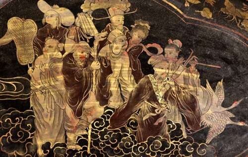 An oval black lacquered tray featuring gilt Chinoiserie decoration of figures on clouds surrounded by a floral border. View V