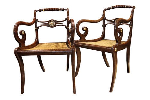 A pair of dark mahogany Regency armchairs featuring swept sabre legs, woven cane seats, rope-twist top rails, and central brass rosette mounts on the backrest splats. View II