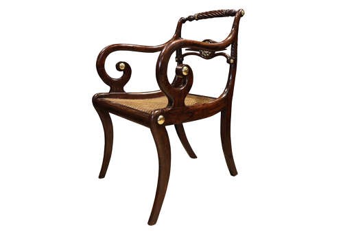 A pair of dark mahogany Regency armchairs featuring swept sabre legs, woven cane seats, rope-twist top rails, and central brass rosette mounts on the backrest splats. View III