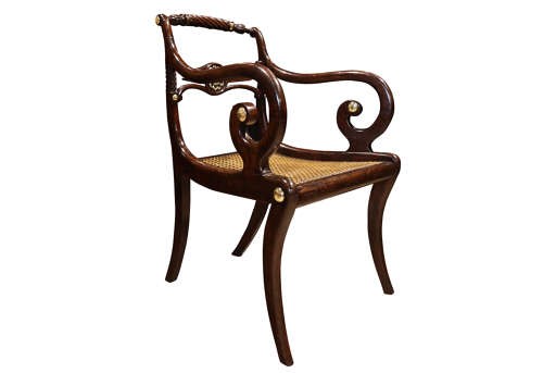 A pair of dark mahogany Regency armchairs featuring swept sabre legs, woven cane seats, rope-twist top rails, and central brass rosette mounts on the backrest splats. View V