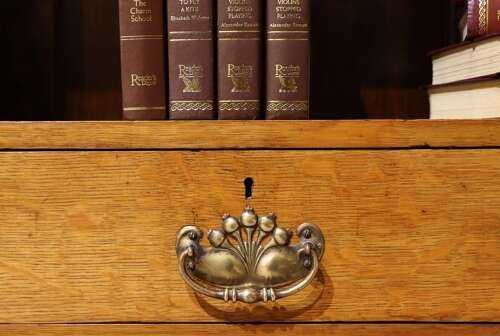Late 19th-century open oak bookcase featuring three tiers of shelving, two lower drawers with brass drop handles, and a moulded top cornice. View VI