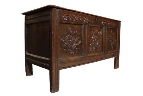 A late 17th-century dark oak coffer with three hand-carved front panels featuring floral rosettes and S-scroll motifs below a lunette frieze. View II