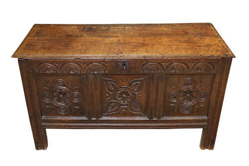 A late 17th-century dark oak coffer with three hand-carved front panels featuring floral rosettes and S-scroll motifs below a lunette frieze. View III