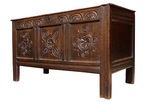 A late 17th-century dark oak coffer with three hand-carved front panels featuring floral rosettes and S-scroll motifs below a lunette frieze. View IV