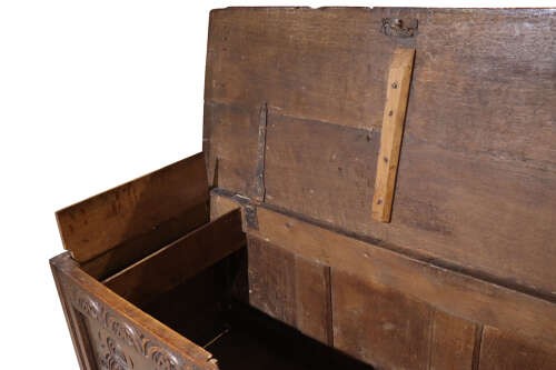 A late 17th-century dark oak coffer with three hand-carved front panels featuring floral rosettes and S-scroll motifs below a lunette frieze. View V