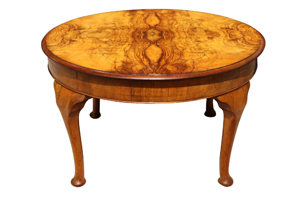 A circular 1920s walnut coffee table featuring a symmetrical book-matched veneer top and slender cabriole legs.