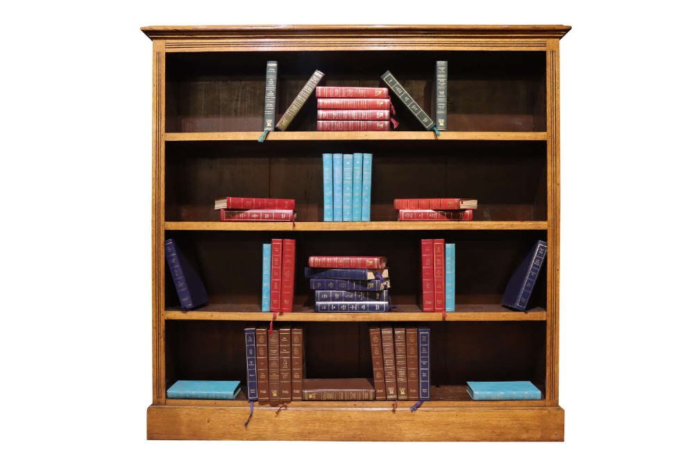 An Edwardian golden oak open bookcase featuring four spacious shelves, a moulded top cornice, and a solid plinth base.