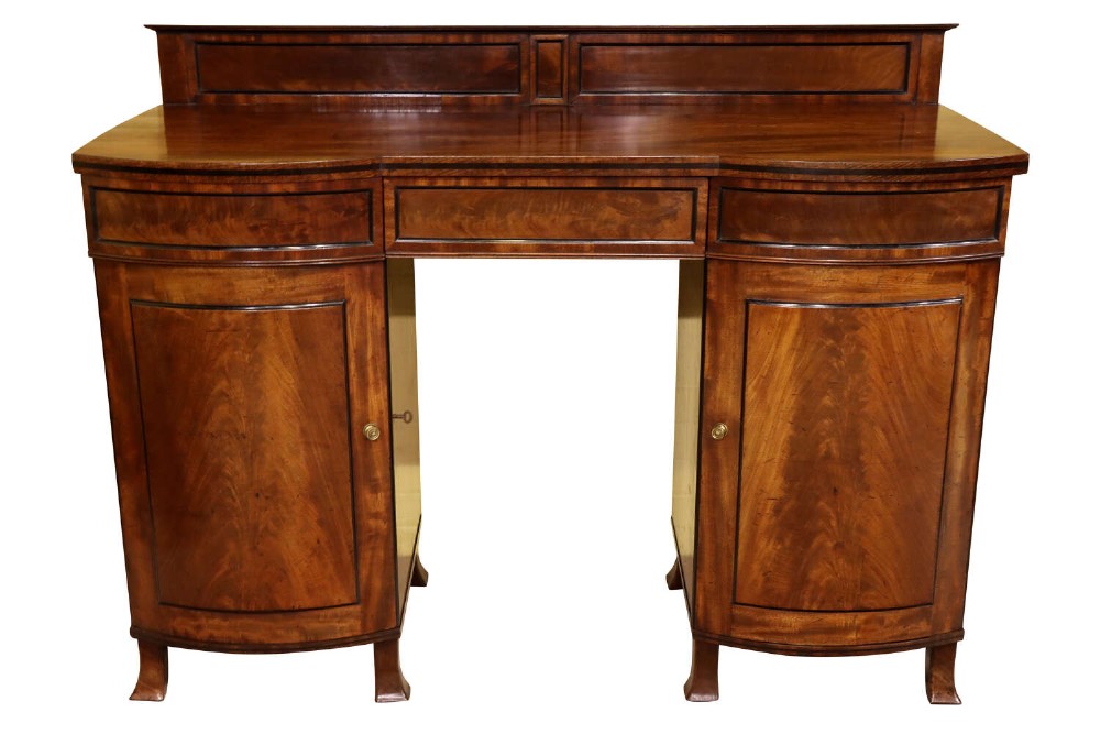 A Regency flame mahogany bow-front pedestal sideboard featuring a low back gallery, central frieze drawer, and two flanking cupboard pedestals on tapered feet.