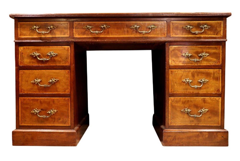 A late Victorian mahogany pedestal desk with satinwood stringing inlay, nine drawers, and brass handles.