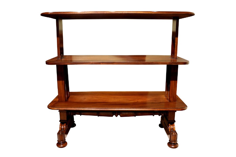A William IV polished mahogany three-tier buffet table featuring a mechanical rise and fall shelf structure supported by double upright columns and a carved trestle base.