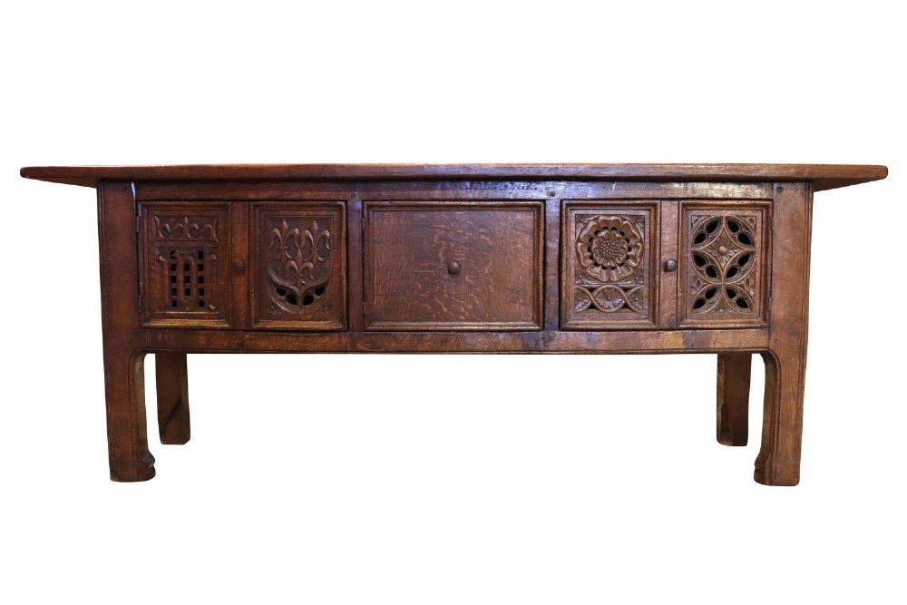 A late 19th-century dark oak Gothic Revival dresser base featuring relief-carved panel doors with geometric tracery and floral motifs.