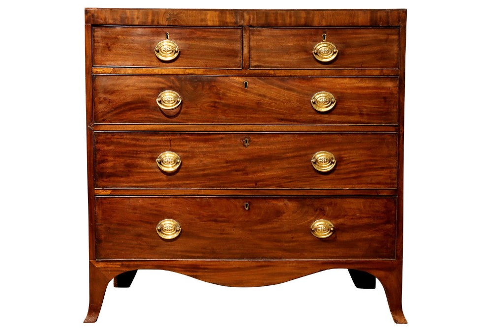 A Regency mahogany chest of drawers featuring two short over three long drawers with oval brass handles and splayed feet.