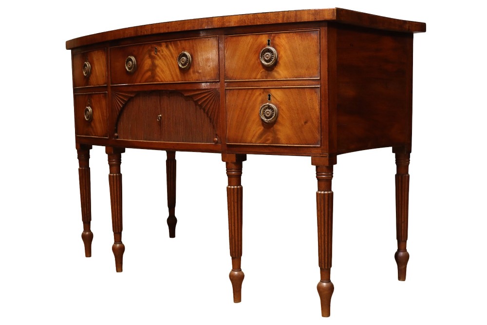 A Regency mahogany bow-fronted sideboard featuring a central drawer with tambour cupboard below, flanked by drawers and supported on six turned, fluted legs. View IV