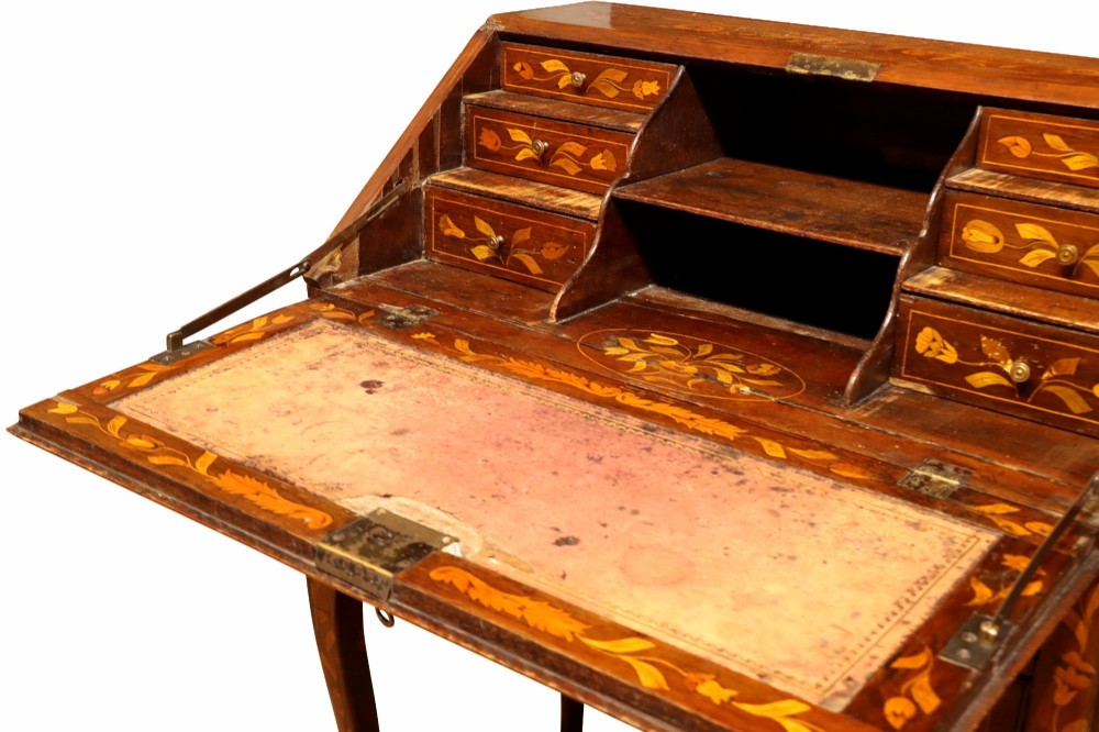 An 18th-century Dutch bureau featuring intricate floral wood marquetry, a sloped fall front, drawers with brass handles, and cabriole legs. View VI
