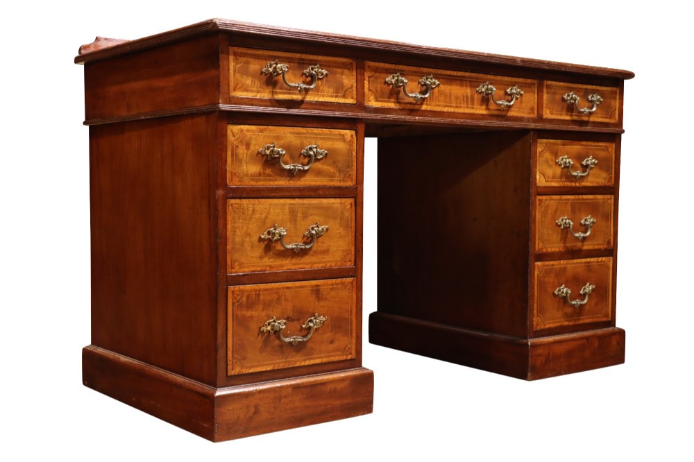 A late Victorian mahogany pedestal desk with satinwood stringing inlay, nine drawers, and brass handles. View II