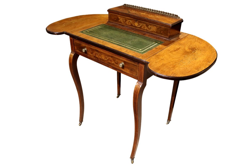 An Edwardian rosewood writing table featuring a green leather writing surface, satinwood floral marquetry inlay, drop-leaf side panels, and a superstructure with brass gallery railing. View IV