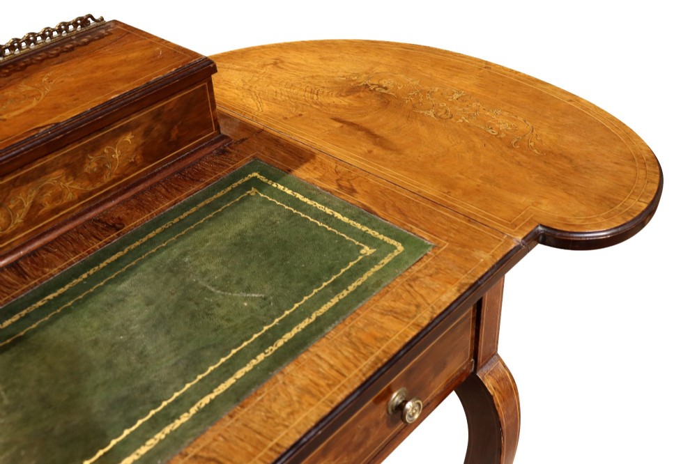 An Edwardian rosewood writing table featuring a green leather writing surface, satinwood floral marquetry inlay, drop-leaf side panels, and a superstructure with brass gallery railing. View VII