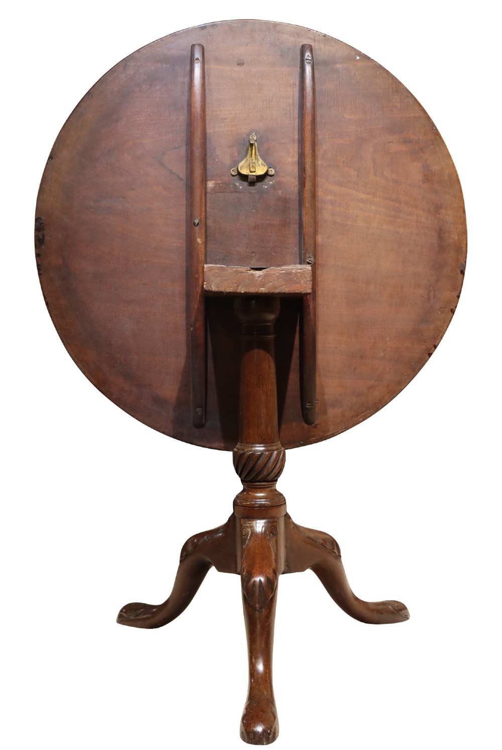 A George IV circular mahogany tilt-top table featuring a turned central column with carved detailing and a tripod base resting on pad feet. View IV