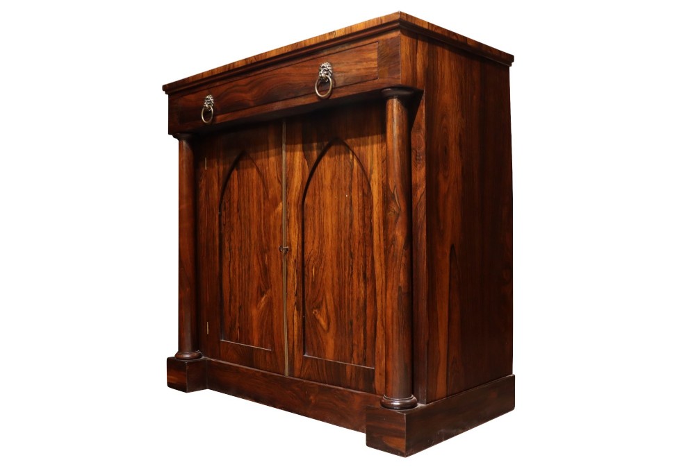 A Regency period rosewood chiffonier featuring two Gothic arched panel doors flanked by turned columns and topped with a single drawer with twin brass lion-head ring handles. View IV