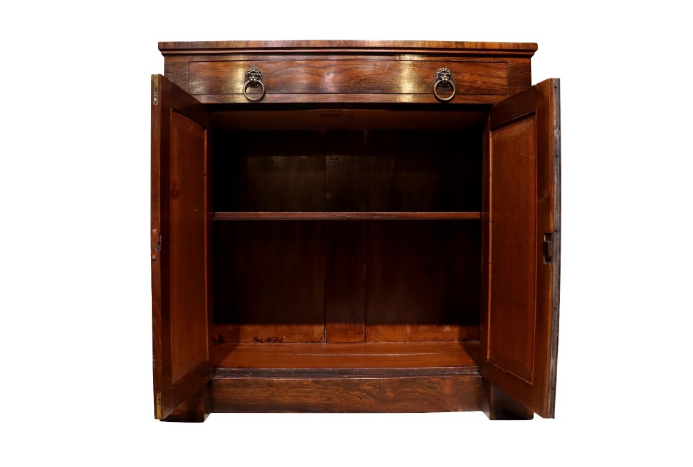 A Regency period rosewood chiffonier featuring two Gothic arched panel doors flanked by turned columns and topped with a single drawer with twin brass lion-head ring handles. View V