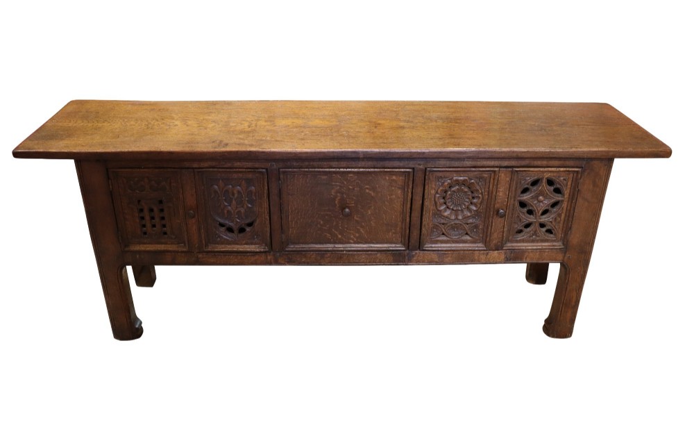 A late 19th-century dark oak Gothic Revival dresser base featuring relief-carved panel doors with geometric tracery and floral motifs. View II