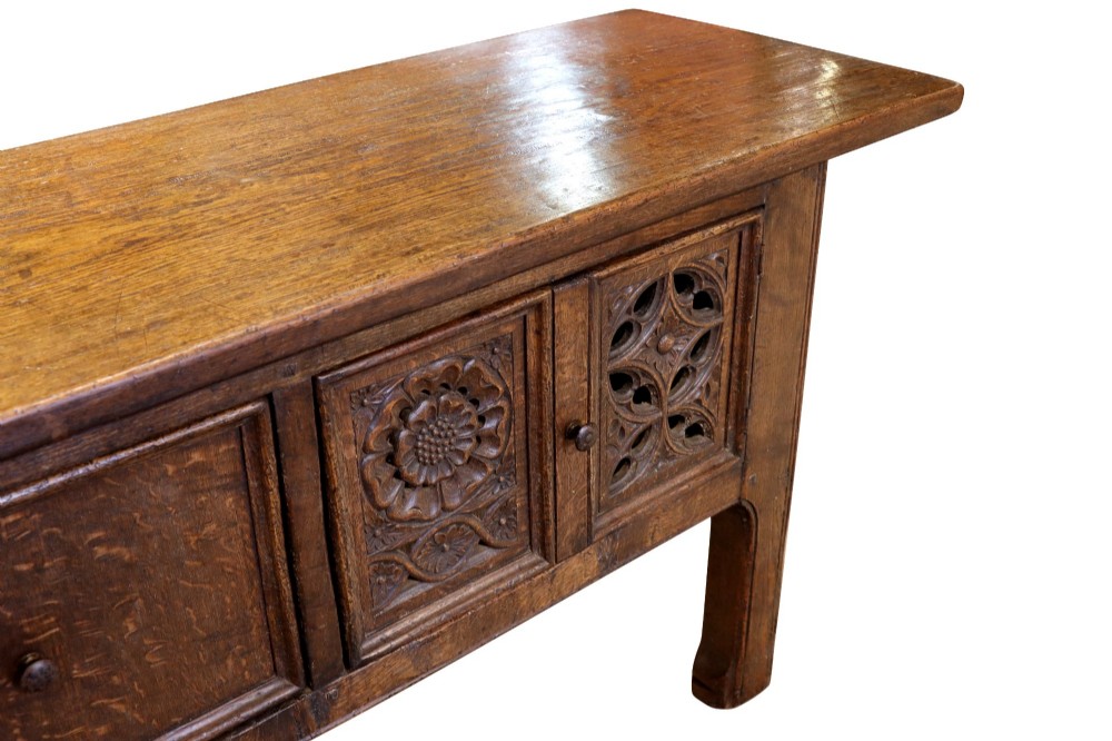 A late 19th-century dark oak Gothic Revival dresser base featuring relief-carved panel doors with geometric tracery and floral motifs. View IV