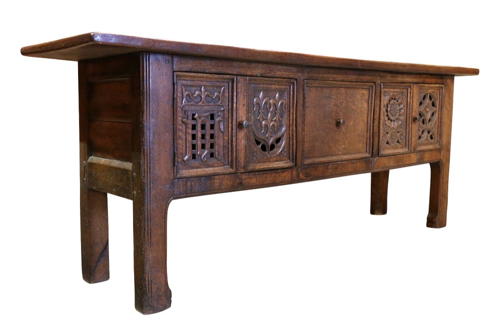 A late 19th-century dark oak Gothic Revival dresser base featuring relief-carved panel doors with geometric tracery and floral motifs. View V