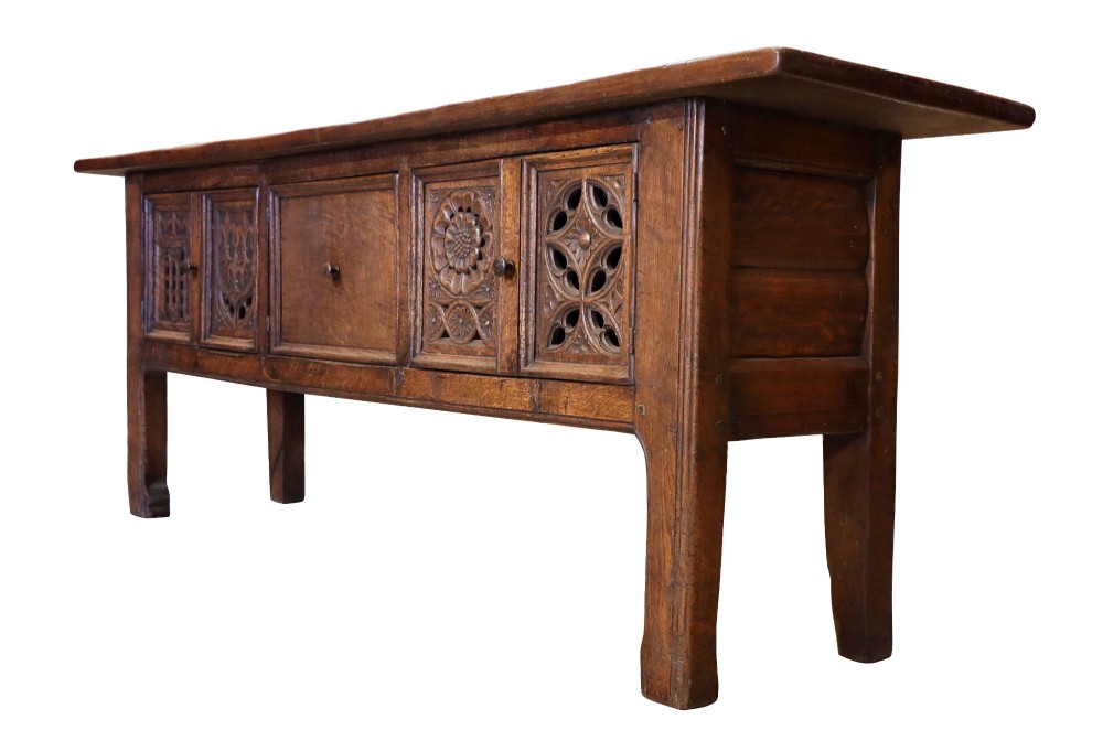 A late 19th-century dark oak Gothic Revival dresser base featuring relief-carved panel doors with geometric tracery and floral motifs. View VI
