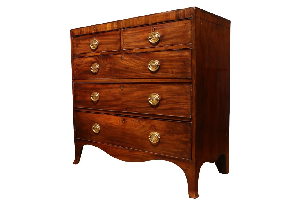 A Regency mahogany chest of drawers featuring two short over three long drawers with oval brass handles and splayed feet. View IV