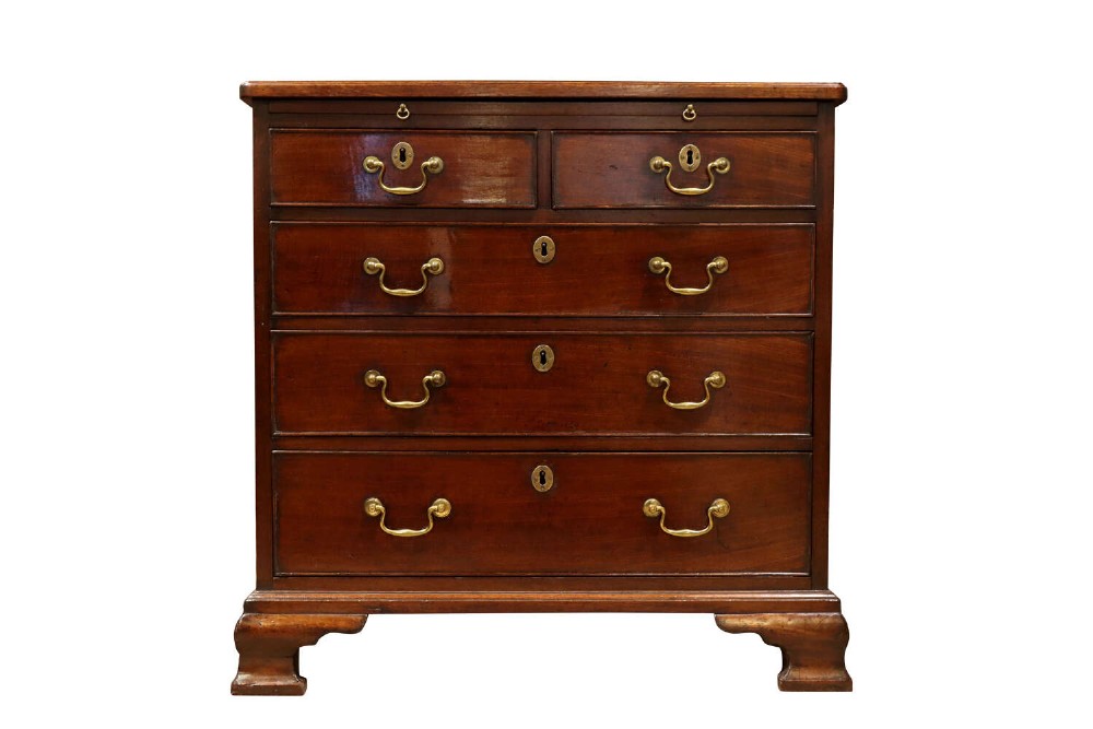 A George III mahogany chest of drawers featuring brass swan-neck handles, an upper brushing slide, and bracket feet.