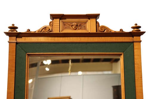 An Edwardian satinwood rectangular wall mirror featuring an inner green fabric border, top pediment with a carved cherub crest, and turned corner finials. View IV