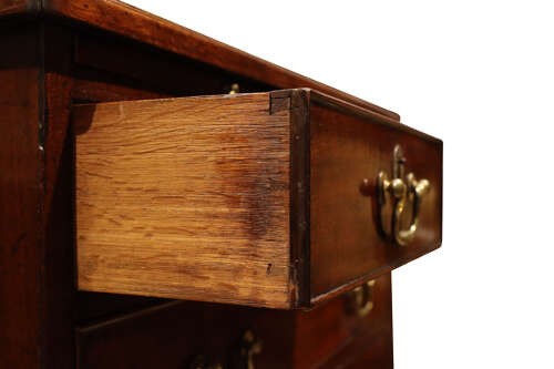 A George III mahogany chest of drawers featuring brass swan-neck handles, an upper brushing slide, and bracket feet. View V