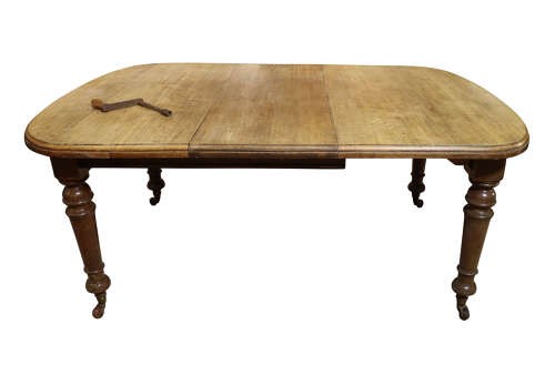 A Victorian oak extending dining table featuring rounded D-ends, a removable centre leaf, and four turned legs on brass castors. View III