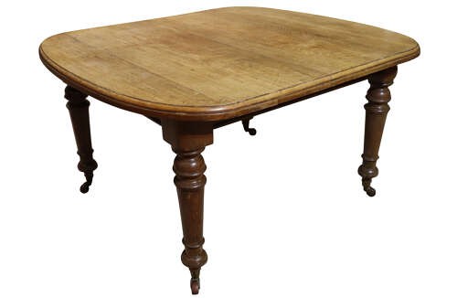 A Victorian oak extending dining table featuring rounded D-ends, a removable centre leaf, and four turned legs on brass castors. View V