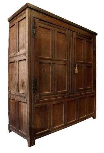 A seventeenth-century dark oak vestment cupboard featuring twin panelled doors with iron hinges above a lower panelled base. View II