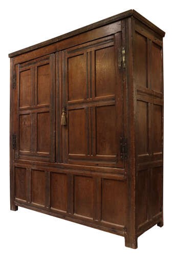 A seventeenth-century dark oak vestment cupboard featuring twin panelled doors with iron hinges above a lower panelled base. View IV