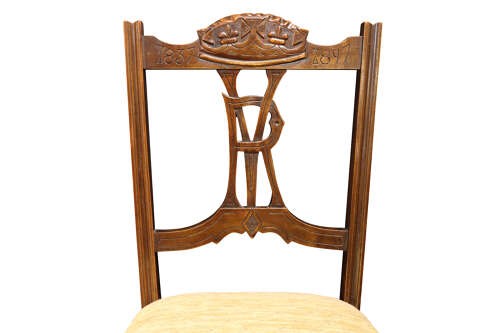 A pair of Victorian carved walnut side chairs with openwork backrests displaying a carved royal crown and monogram, resting on turned front legs with upholstered seats. View V