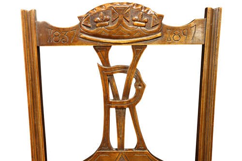 A pair of Victorian carved walnut side chairs with openwork backrests displaying a carved royal crown and monogram, resting on turned front legs with upholstered seats. View VI